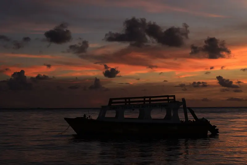 A glass-bottom tour boat used for trips out to Buccoo Reef rides at anchor off Tobago at dusk, the reef and the diving beyond it Tobago's real draw over Trinidad's industrial Chaguaramas.