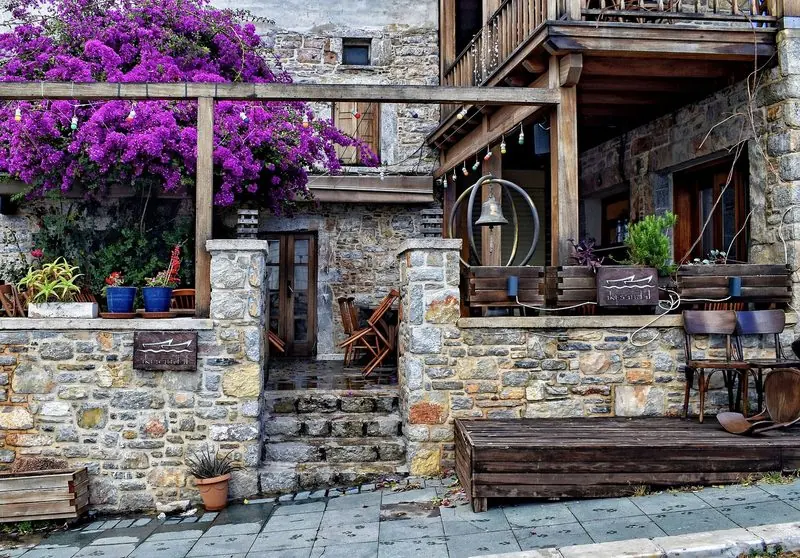 Stone walls and bougainvillea front a small terrace restaurant set back a lane or two from the water, tables still folded before evening service.