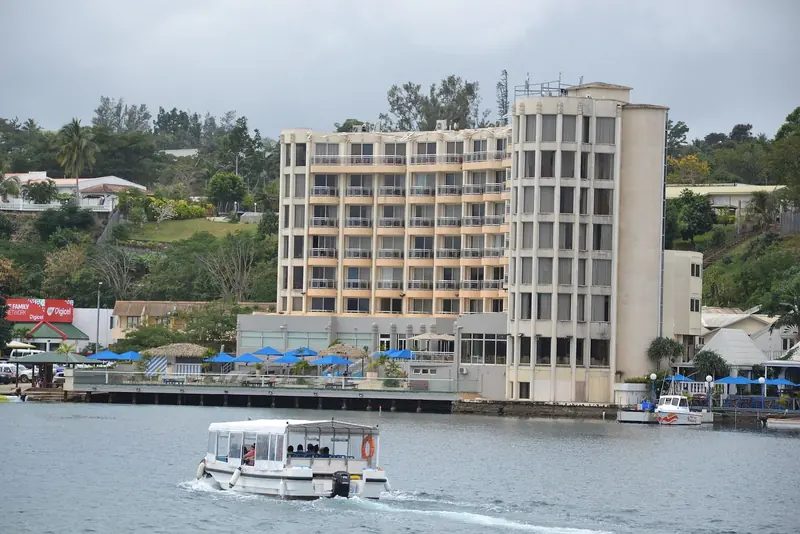 Port Vila's harbourfront, with a passenger launch crossing the inner harbour past the town's waterfront hotels.