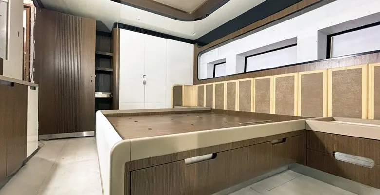 A guest stateroom under construction, walnut joinery going in around the berth frame.