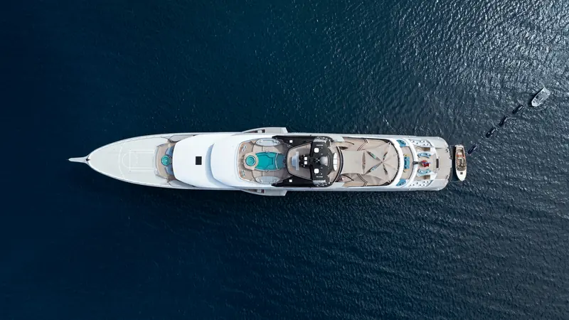 Seen from above, Whisper's five decks run from a forward helipad and sports court to an aft swim platform, with jet skis and tenders lined up off her stern.