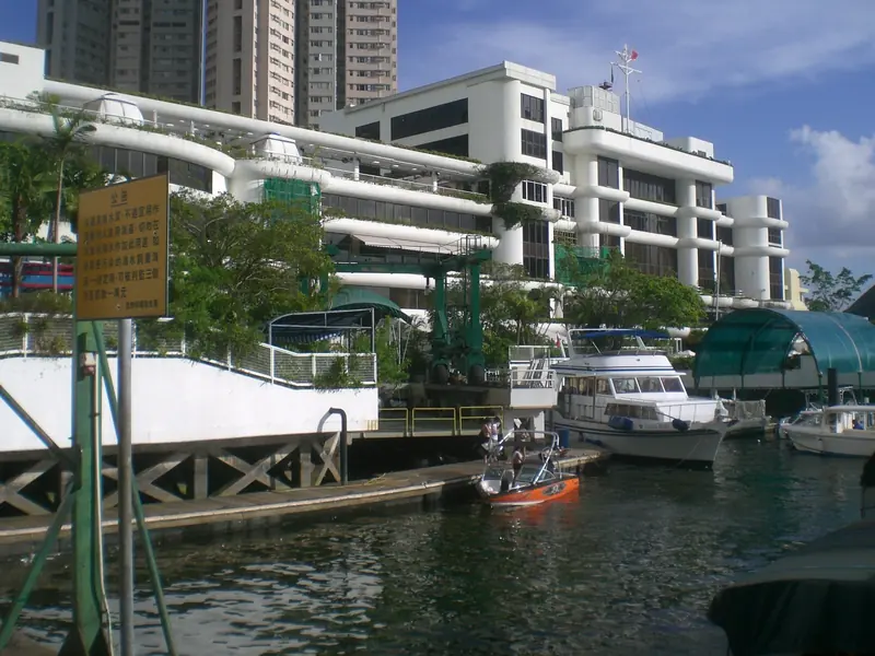 The club's own pier and clubhouse building, flying the Hong Kong flag, with the motor yacht Marina Pearl and other members' boats tied up alongside the pontoon.