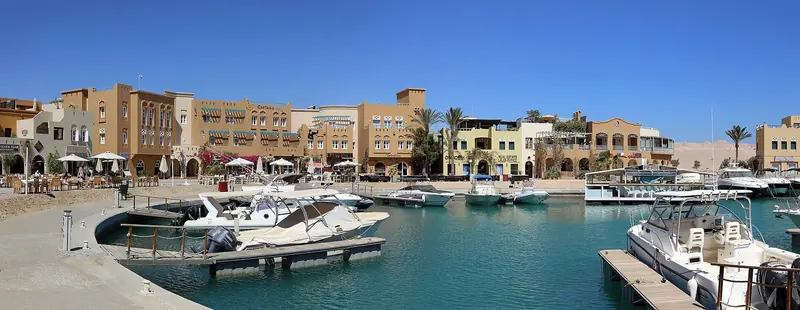The quay by Captain's Inn, cafe tables and umbrellas out front of Il Gelato and the marina's shops.