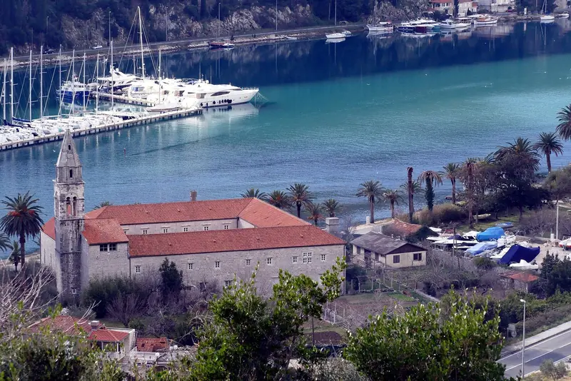 The marina's berths and a motor yacht seen from the hillside above Rozat, with the bell tower of the village's monastery in the foreground - the landmark ACI's own site names as the point where the inlet narrows.