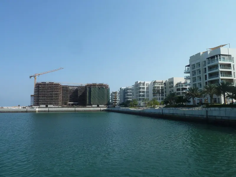 Cranes on the marina front. The residential build-out around the water is the business here, and the berths came with it.