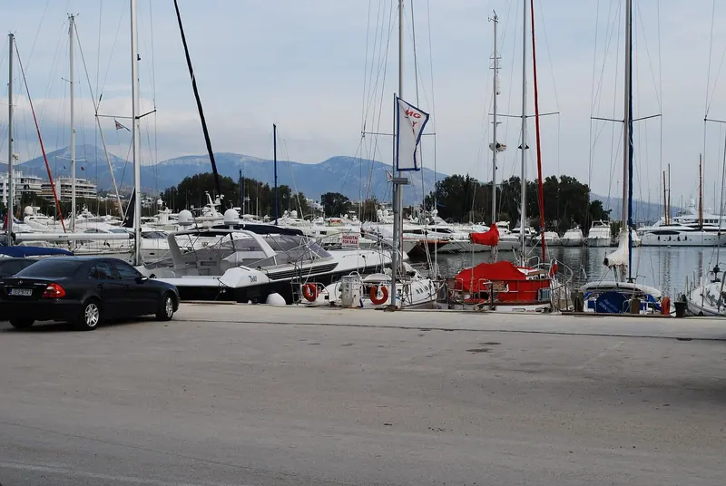 The quay at Alimos Marina, permanent berths lying bow-to with local motor yachts and sailboats, one flying an MG Yachts charter burgee.