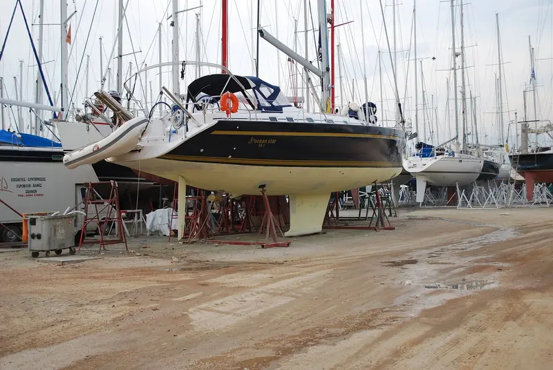 Ocean Star 56.1 up on props in the Alimos Marina boatyard, mast still stepped, a repair van and yard debris around the hardstanding.
