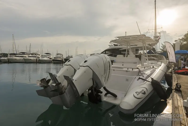 Twin Mercury Verado outboards on a RIB tender named Airship at the dock, backed by rows of sailing yachts in Ao Po Grand Marina's basin.