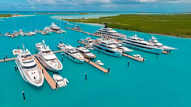 Superyachts and motor yachts on the floating docks at Blue Haven Marina, with the mangrove-lined Leeward Going Through channel behind