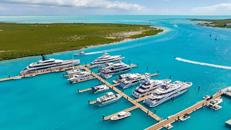 Aerial view of Blue Haven Marina's finger docks at the mouth of the Leeward Going Through channel, with tenders running the cut to Grace Bay