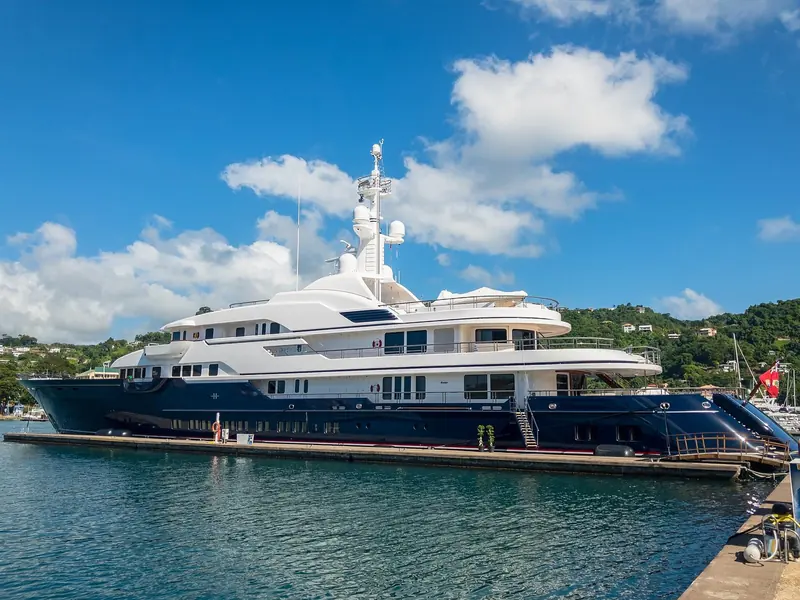The motor yacht Hampshire II on a finger berth at Port Louis Marina, St George's, with the marina's own mast forest visible astern and Grenada's hills behind.