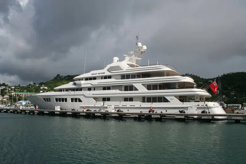 Ocean Victory alongside the same floating pontoon system, storm light over the hills behind St George's Lagoon.