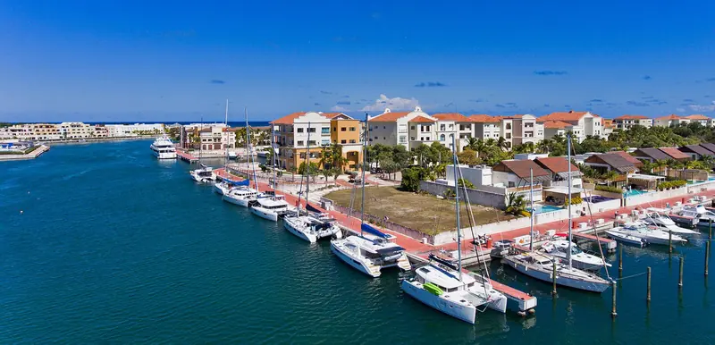 Catamarans and sailboats on the outer quay, with the marina's waterfront apartment buildings behind.