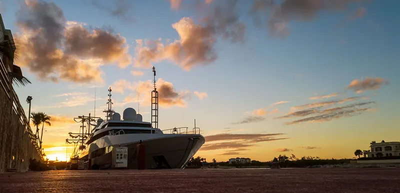 A superyacht docked on the quay at Marina Cap Cana at sunset.