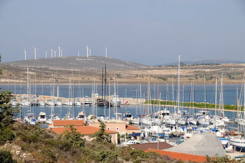 The marina's pontoons, packed with yachts, with the Alacati wind farm turning on the hills behind.