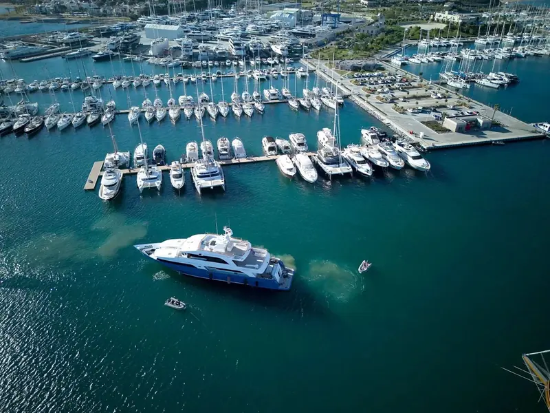 A superyacht on the outer hammerhead, dwarfing the charter fleet moored around it.