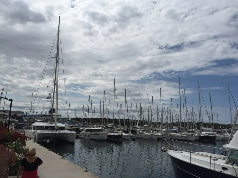 Catamarans and cruising yachts fill the inner basin, and the boatyard cranes at the head of the quay show this is a working yard as well as a berth.