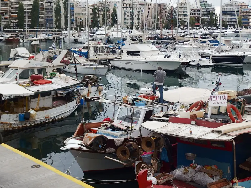 Small open boats and day launches moor in the foreground while sport-fishing convertibles and a motor yacht sit on the pontoon behind, the everyday mix that Zea's berth-by-length tariff has to price for.