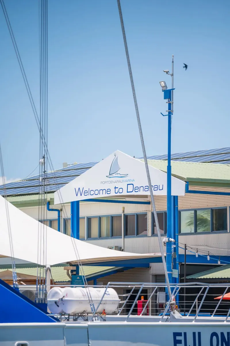 The Welcome to Denarau sign at the marina entrance, where sailing yachts and day-charter catamarans share the docks