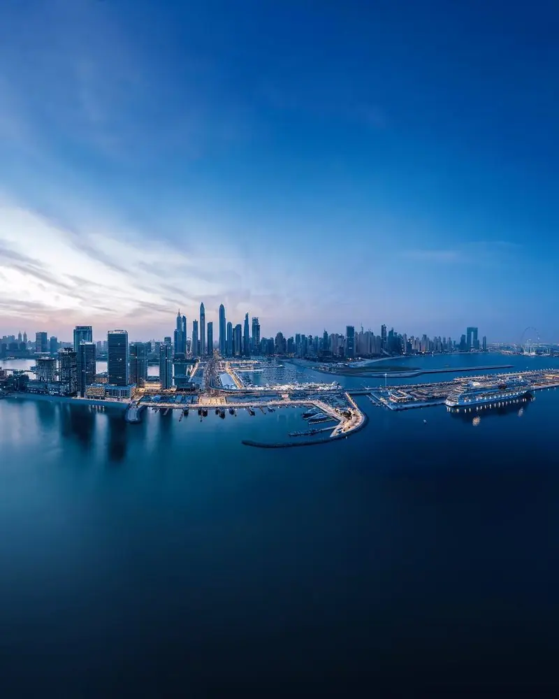 Seen from above at first light, the harbour arms reach out into still water below the city towers.