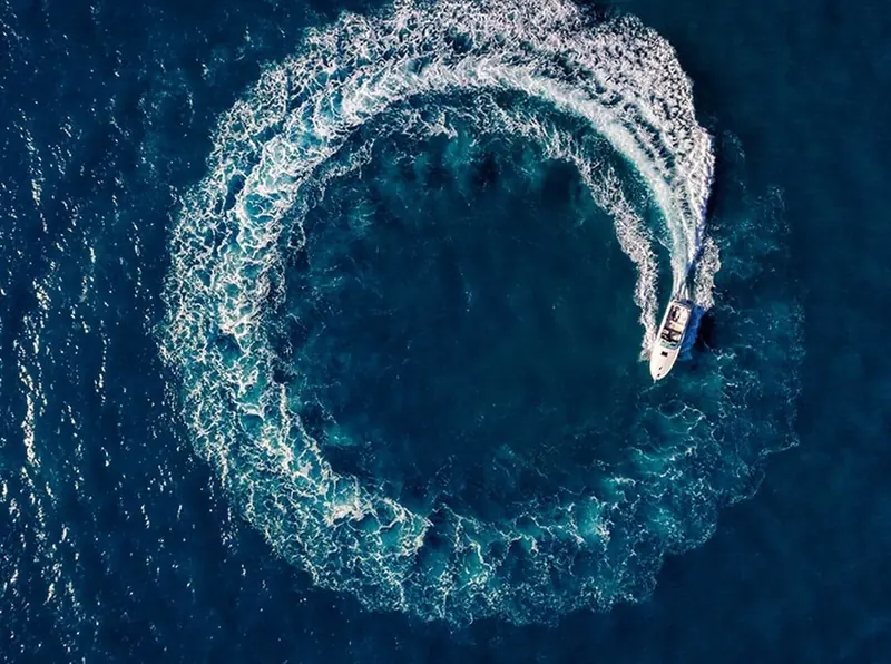 Flisvos Marina's own drone shot of a tender carving a full circle in open water, the wake ring closing back on itself around the boat.