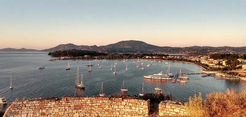 Corfu Town from the fort at sunrise, with boats anchored off. The town is about 7 km down the coast from the marina.