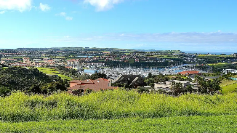 Gulf Harbour Marina and Village seen from the hillside above, with the wider Hauraki Gulf beyond.