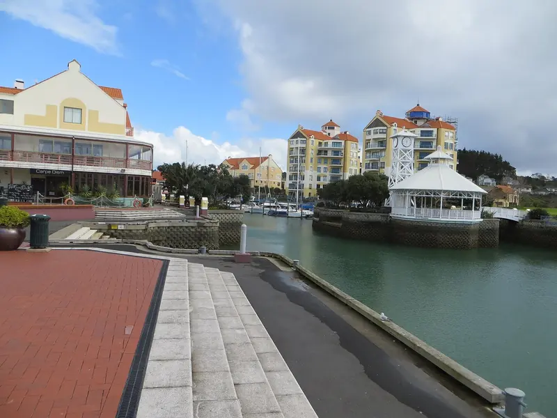 Gulf Harbour Village's waterfront, with the Carpe Diem restaurant and a clock-tower gazebo beside the inner basin.