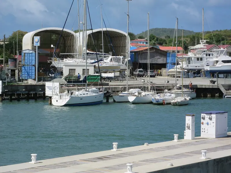 The IGY-run boatyard beside the marina: mobile boat hoists, a hardstand of yachts on props, and the blue storage containers cruisers rent for gear during a haul-out. IGY signage is visible on the dock board.