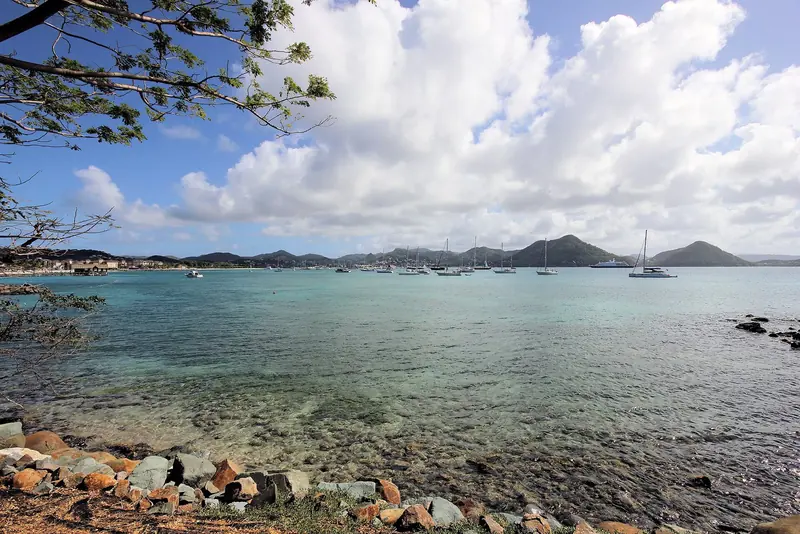 The wider Rodney Bay roadstead seen from Pigeon Island, where yachts still anchor outside the marina gate rather than pay for a berth. The shallow reef shelf along this point is part of why holding in the anchorage is patchy.
