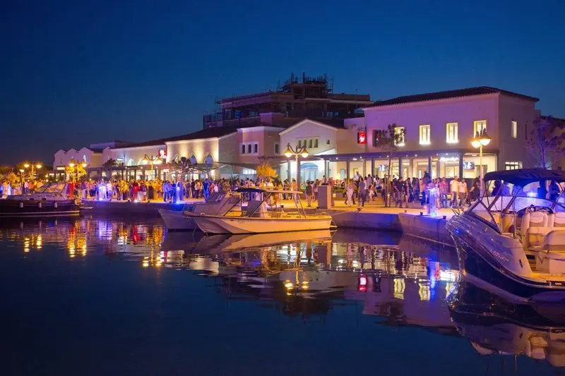 Motor yachts take the promenade berths at dusk while the crowd fills the quay behind them, which is how the marina looks on a summer evening.