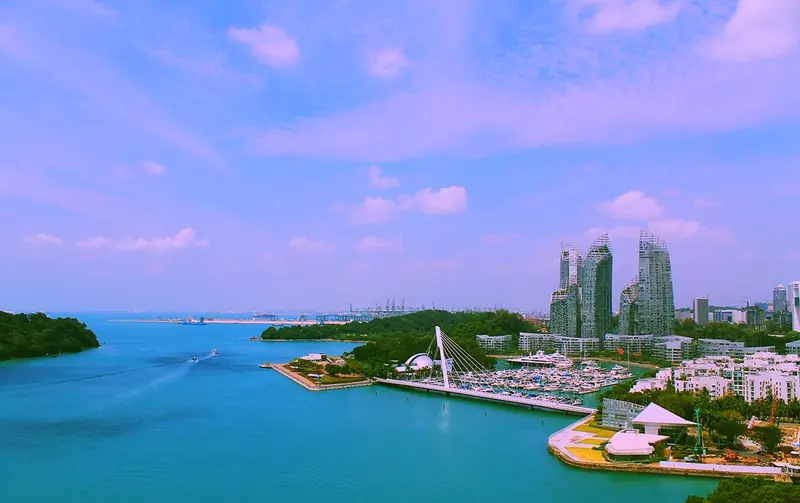An aerial view of the whole site: the marina basin, the cable-stayed Keppel Bay Bridge, the Reflections at Keppel Bay towers under construction, and Keppel Terminal's cranes in the distance.