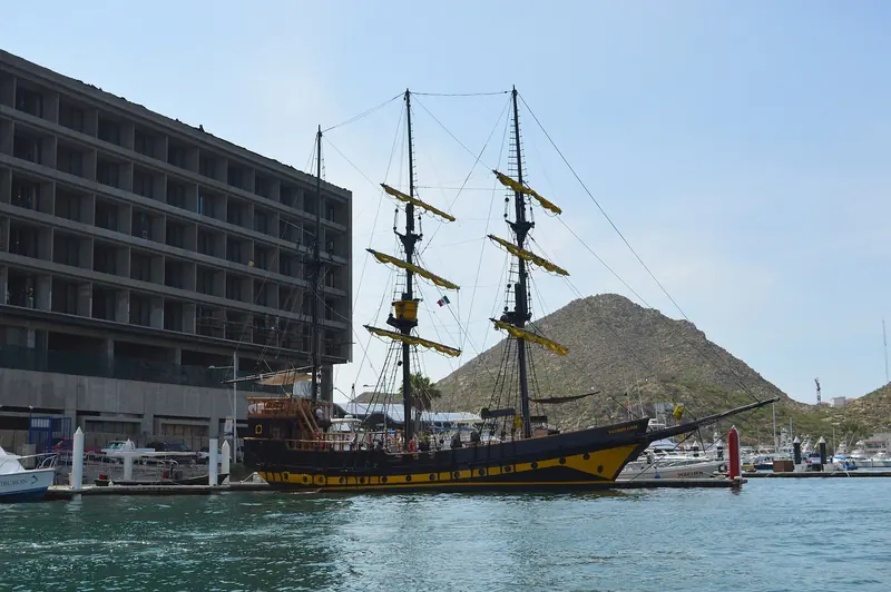 A tall ship tied up against the marina hotel frontage, part of the working tourist fleet that shares the basin with private yachts.