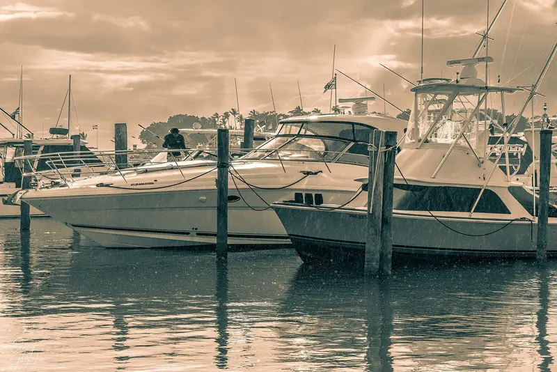 Sportfishing boats on the pontoons during a squall, a reminder of the wet-season weather the resort's own hurricane guidance is written for guests, not for a berthed yacht.