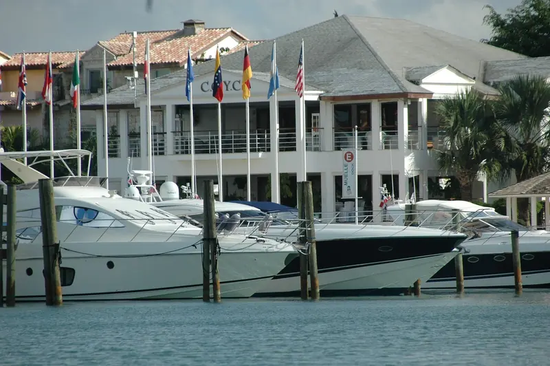 The Casa de Campo Yacht Club clubhouse on the marina, dock E, with a run of flags and sportboats on the pontoon in front of it.