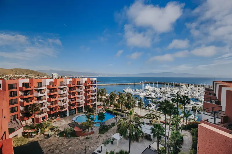 The salmon-colored Hotel Coral & Marina tower over its own marina basin, with hillside Ensenada climbing the slope behind.
