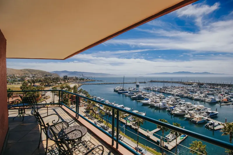 The view from a guest-room balcony over the breakwater and slips, with the commercial port's container cranes visible across the bay.