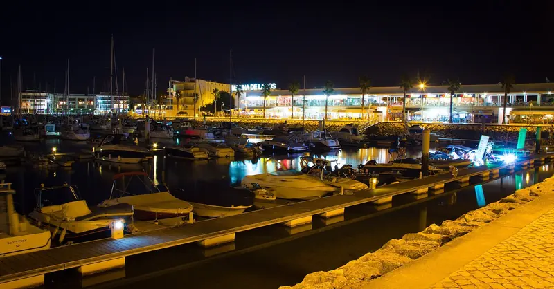 Marina de Lagos at night, masts lit along the pontoons on the Bensafrim estuary.