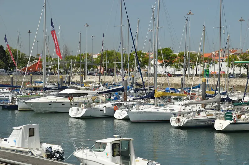 Cruisers and sailing yachts including Cormoran, Whatever and Marear rafted along the visitor pontoons, TagusCruises flags flying over the quay behind them.