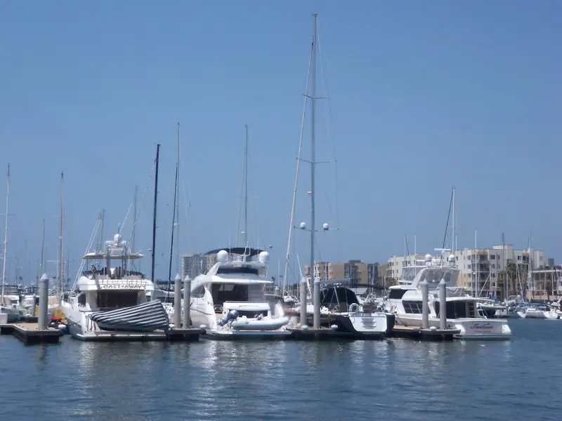Motor yachts tied up in the marina, with condominiums lining the basin behind them.
