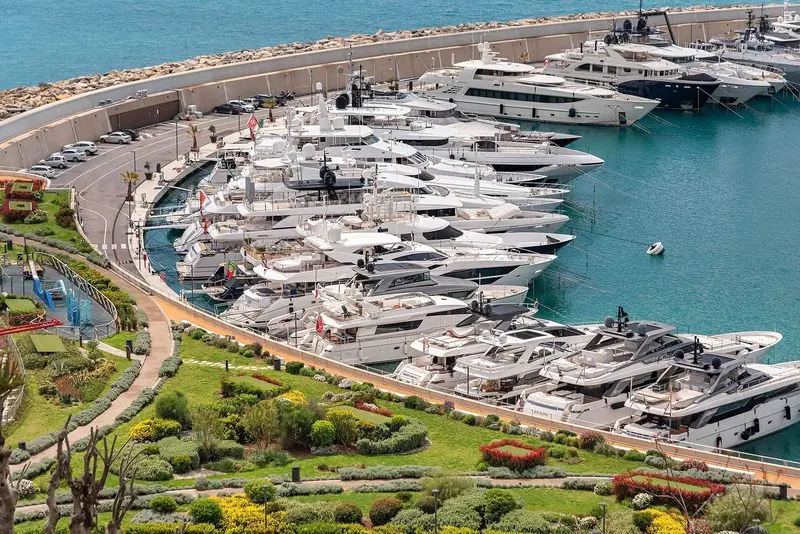 Superyachts lie stern to the curved quay inside the enclosed basin at Cala del Forte, with the outer breakwater taking the weather.