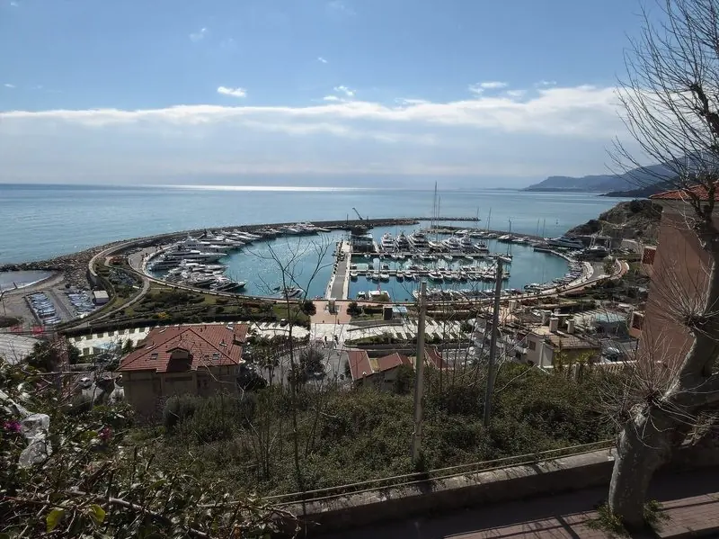 Seen from the hill above, the whole harbour reads as one round pool with pontoons on the inner side and a single narrow entrance to the sea.