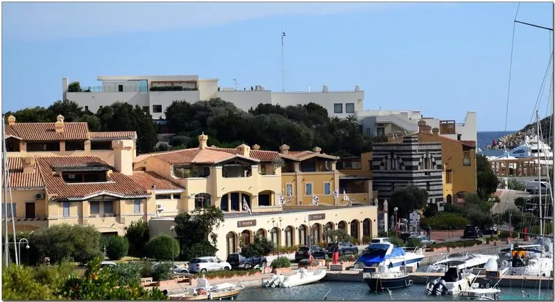 Terracotta houses step down to the water at the head of the bay, a small sand beach on one side and the yacht berths on the other.