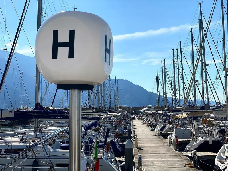 The helipad marker on the finger pier, with sailing yacht masts lined up behind it