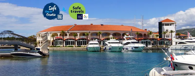 Superyacht berths along the outer quay, with the resort's hotel wing behind them.