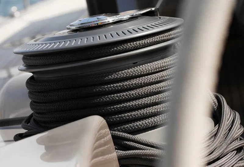 Mooring lines coiled around a polished winch on the deck of a berthed yacht.
