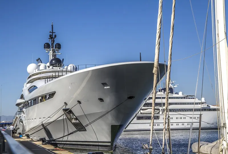 The flared bow of a large motor yacht at the quay wall, a second yacht berthed beyond her.