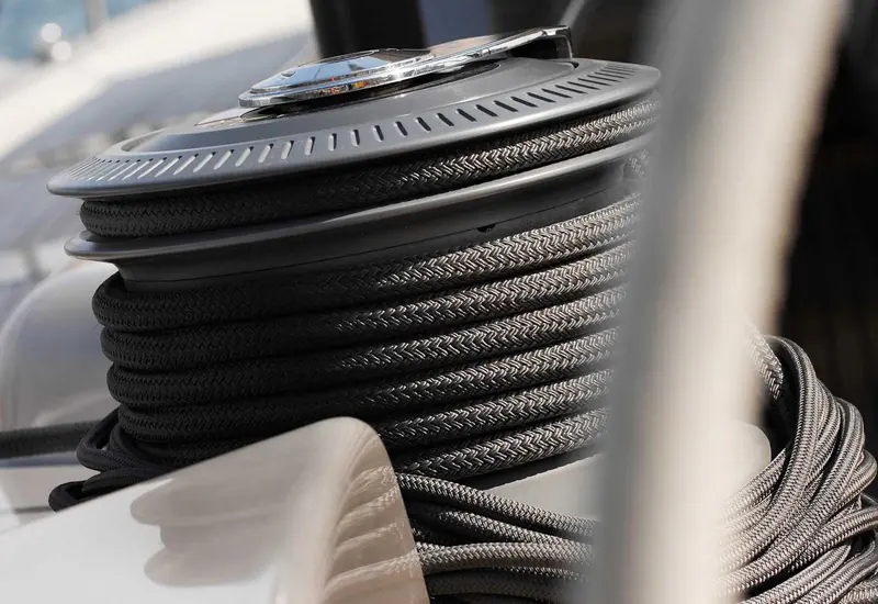 Mooring lines coiled around a polished winch on the deck of a berthed yacht.