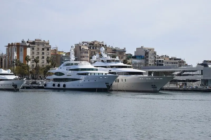 The megayacht quay runs the length of the basin, the marina's own glass clubhouse closing the far end and the city rising straight off the waterfront.