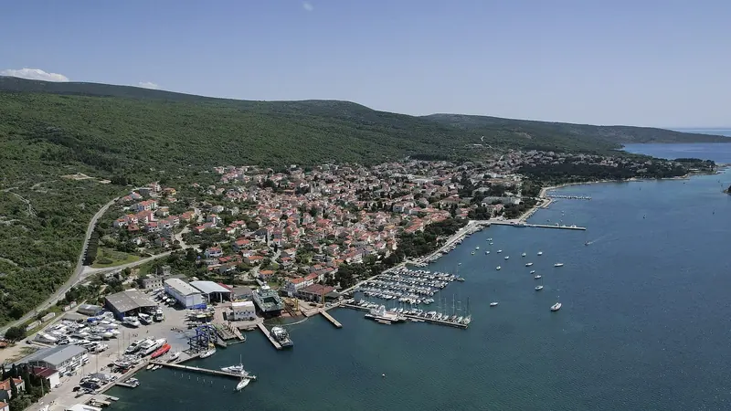Punat and Krk seen from across the bay, the marina's breakwater visible against the shoreline.
